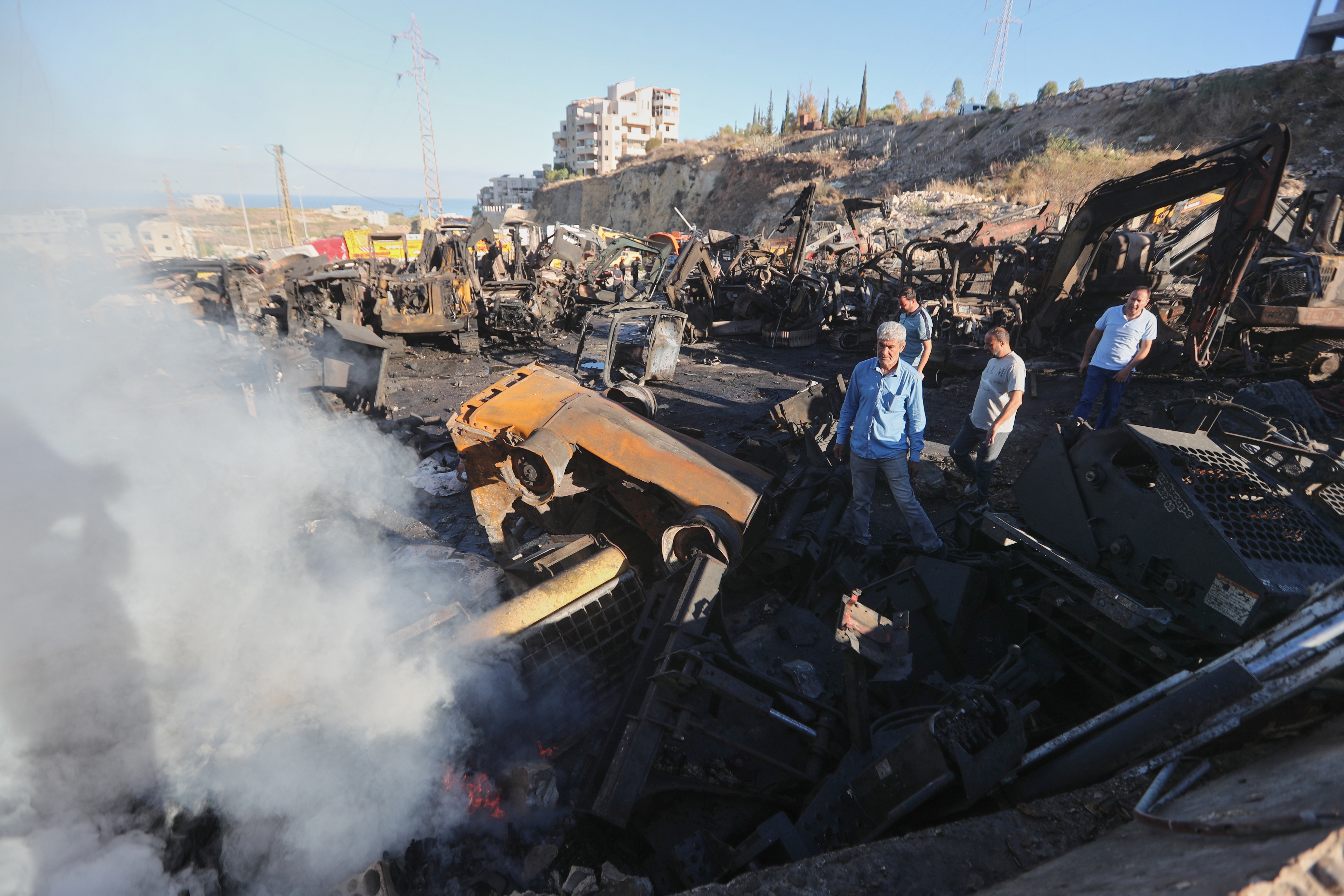 People gather at a site that sold heavy machinery, where a large number of vehicles were destroyed in Israeli airstrikes, in the southern village of Msayleh, Lebanon, Saturday, Oct. 11, 2025.